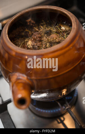 decocting medicinal herbs with enamel pot on gas burner Stock Photo