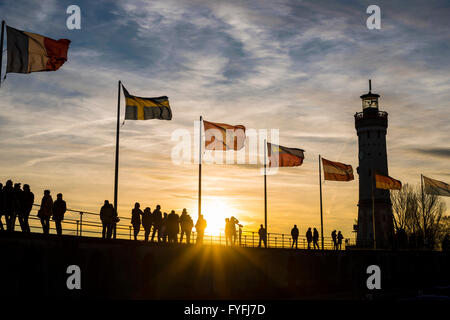 Silhouettes of people and flags at sunset, harbor in Lindau am Bodensee, Bavaria, Germany Stock Photo