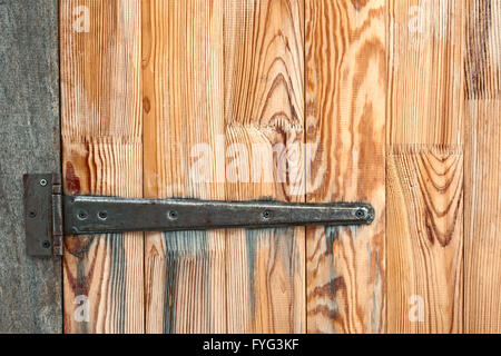 Detail of wooden door with a metal hinge Stock Photo