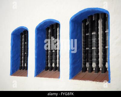 Three windows with blue outlines and whitewashed walls in Sitges, Spain Stock Photo