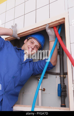 Plumber fixing water supply in public restroom Stock Photo