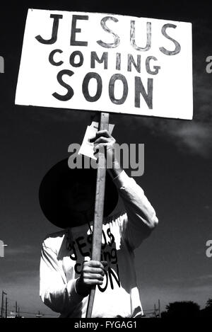 Ghostly looking man holding a sign on the street that reads 'Jesus Coming Soon' Stock Photo