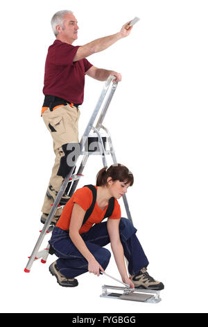 A mature manual worker and his young female apprentice. Stock Photo