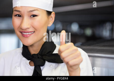 Composite image of portrait of smiling female cook gesturing thumbs up Stock Photo