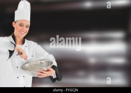 Composite image of happy female chef holding wire whisk and mixing bowl Stock Photo