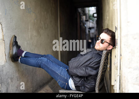 trendy young man shades sitting chair cool alley model release available Stock Photo