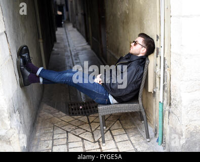 trendy young man shades sitting chair cool alley model release available Stock Photo