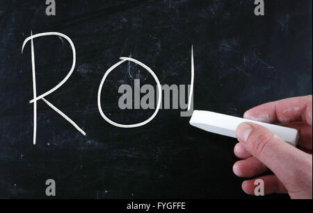 The word ROI handwritten with white chalk on a blackboard Stock Photo