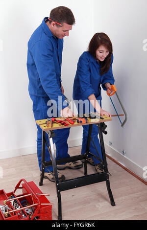 Worker showing an apprentice how to use a hacksaw Stock Photo