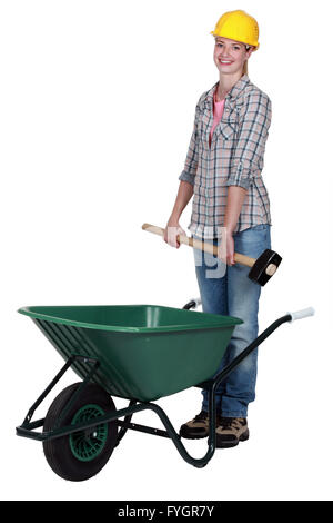 Tradeswoman placing a mallet in a wheelbarrow Stock Photo