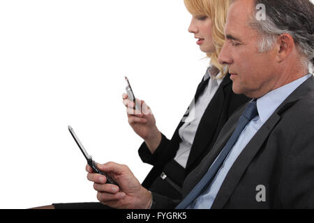 Business partner both checking e-mails on cellphone Stock Photo