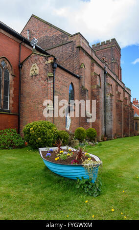 Old rowing boat converted into a flower bed outside a church in Lytham, Lancashire, UK Stock Photo