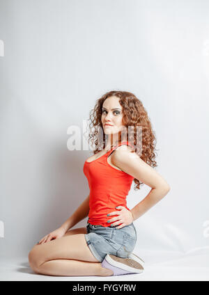 curly brunette on white in red shirt  sitting Stock Photo