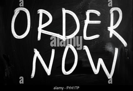 Order now handwritten with white chalk on a blackboard Stock Photo