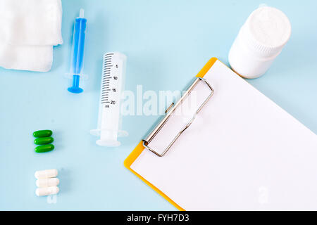 Medical conceptual picture with pills, injection, gauze, bottle, empty clipboard sheet. Stock Photo