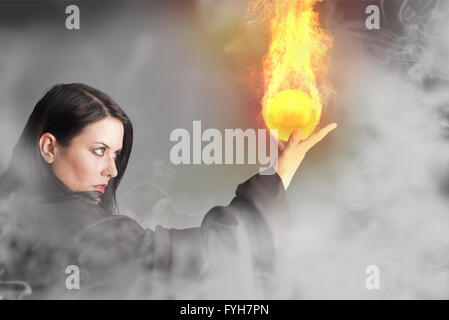 Magician woman with a fire ball in her hands Stock Photo