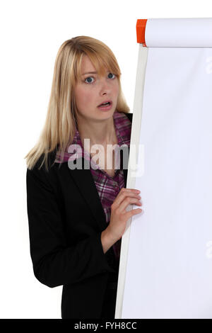 Shocked blond woman stood by blank flip chart Stock Photo