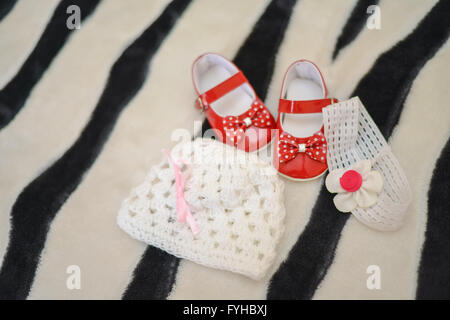 Red shoes, cap and headband girls sat on the bed Stock Photo