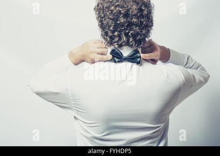 Bow tie on the back side. Strange or fun concept. Back view of an elegant young fashion man in tuxedo , toned image Stock Photo