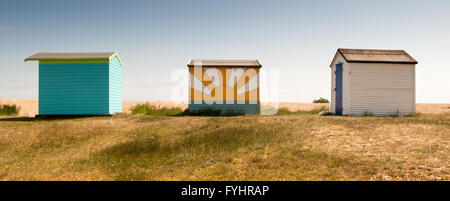 A triplet of beach huts at New Romney in Kent. One beach hut is plainted with a sun mural. Stock Photo