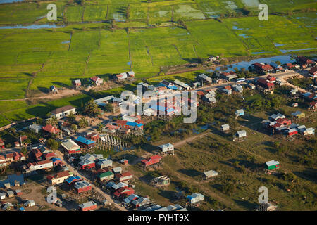 Village of stilt houses that are seasonally flooded, and rice fields, Phnom Krom, near Siem Reap, Cambodia - aerial Stock Photo