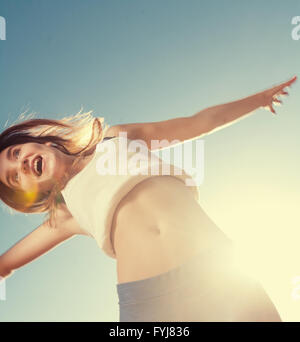 Blonde teenager girl jumping happy in the mountain with the blue sky in ...