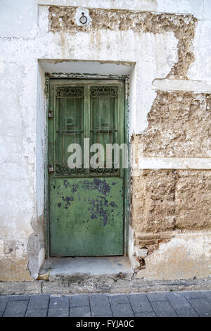 White wall with texture, green wooden door Stock Photo