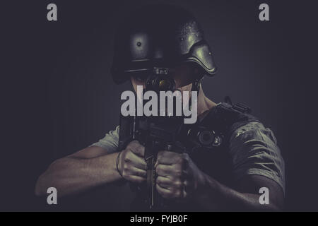 Security, paintball sport player wearing protective helmet aiming pistol ,black armor and machine gun Stock Photo