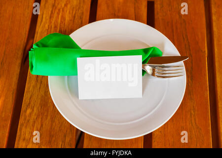 Dishware and blank paper card on table in restaurant Stock Photo