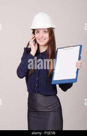 Builder in helmet talking but phone with a folder hands Stock Photo