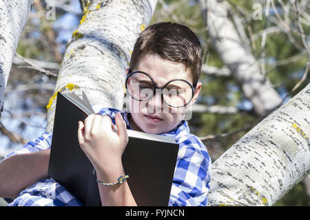 Student boy reading a book in the woods with shallow depth of field and copy space Stock Photo