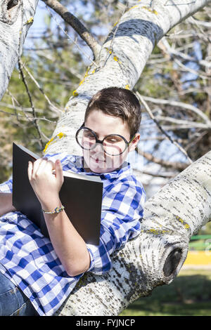 School.Huge glasses.Student boy reading a book in the woods with shallow depth of field and copy space Stock Photo