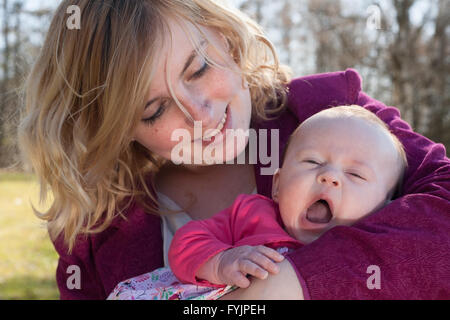Baby is yawning in mothers arms Stock Photo