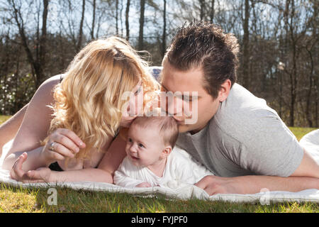 Young parents are kissing the baby Stock Photo