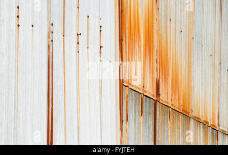 Metal siding overlapping with rust stains running down vertically from screws and rivets. Stock Photo