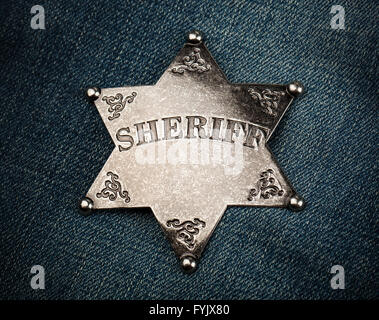 Sheriff star badge on blue denim background Stock Photo