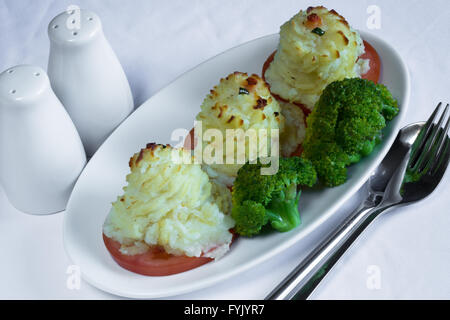 A serving of homemade Duchess Potatoes on griddled Tomato with a side of steamed Broccoli. Stock Photo
