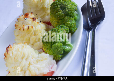 A serving of homemade Duchess Potatoes on griddled Tomato with a side of steamed Broccoli. Stock Photo