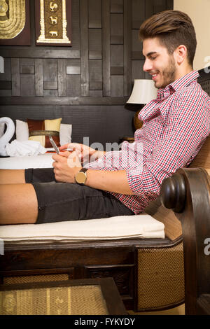 Young man using a tablet pc in a asian hotel room Stock Photo