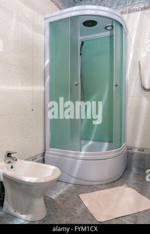 Modern en suite bathroom with large shower, toilet and wash basin in beige natural with natural stone tiled walls Stock Photo