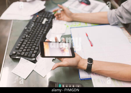 Close up of hand of business man working document and using mobile smart phone in office . Stock Photo