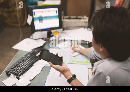 Close up of hand of business man working document and using mobile smart phone in office . Stock Photo