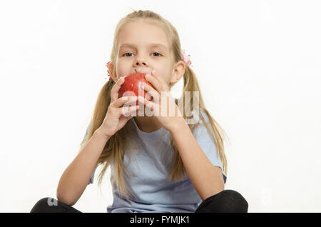 Six year old girl sitting and eating an apple Stock Photo
