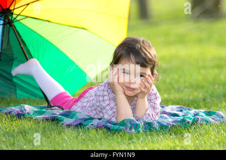 little girl with a rainbow umbrella in park Stock Photo