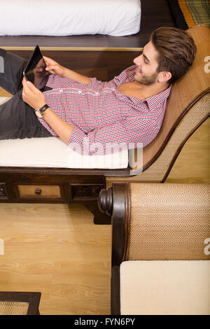 Young man using a tablet pc in a asian hotel room Stock Photo