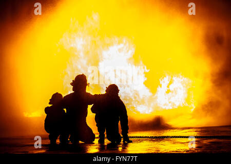 Firefighters in front of a burning tank