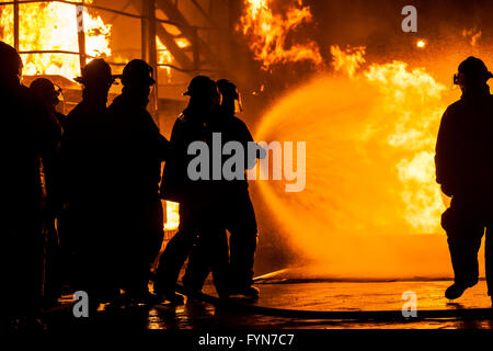 Firefighters putting out burning structure with water Stock Photo