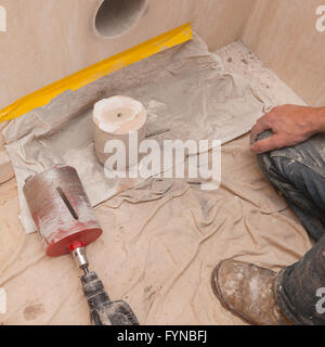 A builder drills a hole through wall for a 4 inch soil pipe showing the core in the Uk Stock Photo