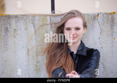 A woman sitting outside with long wind blown red hair. Stock Photo