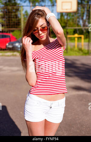 Beautiful young woman, outdoors, resting bright red T-shirt, fashion style, happy brunette hair straightening Stock Photo